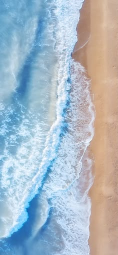 an aerial view of the ocean with waves crashing on the shore and people walking along the beach