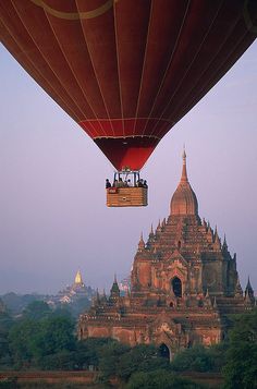 a hot air balloon flying over a large building with spires in the background at dusk