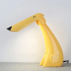 a yellow desk lamp sitting on top of a white floor next to a black cord