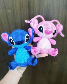 two small crocheted stuffed animals sitting next to each other on a person's hand