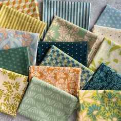 many different types of fabric are laid out on the floor, including one in blue and green