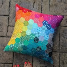 a person laying on the ground with their feet up next to a multicolored pillow