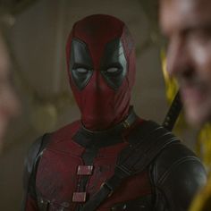 the deadpool character is standing in front of two men