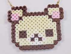 a brown and white cat is on a gold plated necklace with pink dots around it