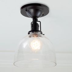 a clear glass dome light fixture hangs from the ceiling in a room with white walls