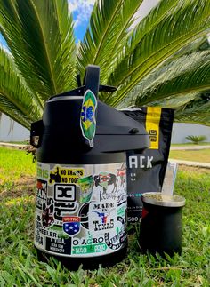 a crock pot sitting in the grass next to a palm tree with stickers on it