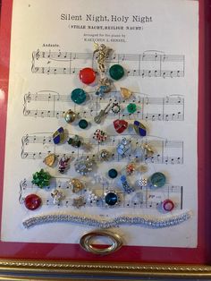 a christmas tree made out of buttons and other items on a sheet of music paper