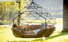 a woman laying in a swing chair reading a book