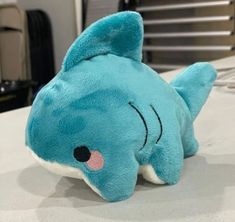 a blue stuffed shark laying on top of a bed