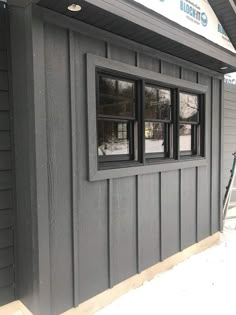 the side of a building that has windows on it and is being painted gray with black trim