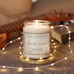 a lit candle sitting on top of a table next to a string of lights and a guitar