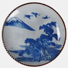 a blue and white plate with birds flying in the sky