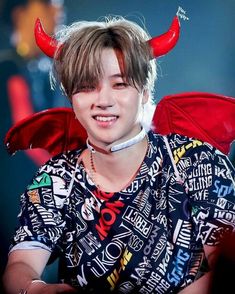 a young man with horns on his head wearing a shirt that has letters all over it