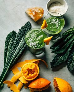 green smoothie with oranges, kale and other ingredients on a table top