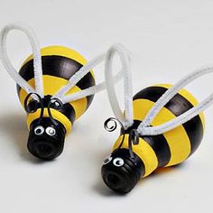 two black and yellow bees with eyes painted on each one's body, tied together by twine