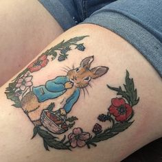 a rabbit tattoo on the side of a woman's thigh, with flowers around it