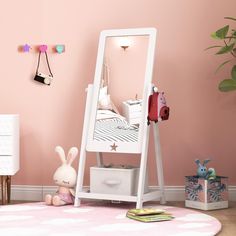 a white mirror sitting on top of a pink floor next to a dresser and toy