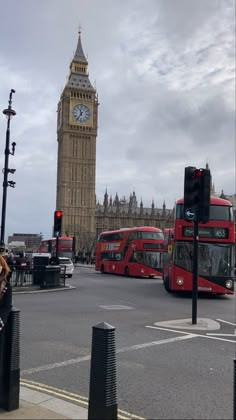 the big ben clock tower towering over the city of london as traffic passes by on a cloudy day