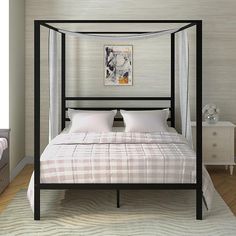 a four poster bed in a bedroom with white walls and wood flooring, along with two nightstands on either side of the bed