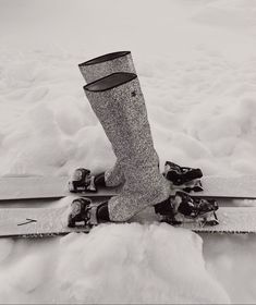 a pair of skis sitting on top of snow covered ground next to a person's boot