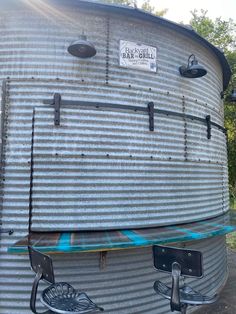 a large metal tank sitting on top of a cement ground next to trees and bushes