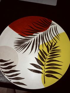 a plate with leaves painted on it sitting on a counter top next to a knife and fork