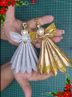 two christmas angel ornaments being held by someone's hand