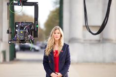 a woman standing in front of a camera with her hands on her hips and looking at the camera