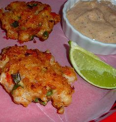 some food is on a pink plate with a lime and a bowl of dipping sauce