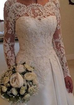 a woman in a white wedding dress holding a bridal bouquet and looking at the camera