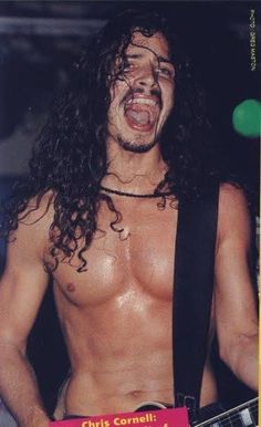 a shirtless man with long hair and no shirt holding a guitar