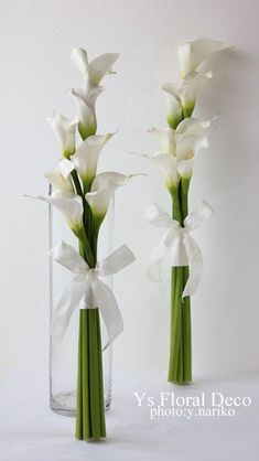 two clear vases with white flowers in them