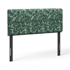 an upholstered headboard with black metal legs and green leaves on the back