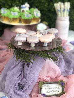 a table topped with lots of desserts on top of a metal tray covered in grass