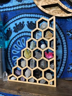 a wooden shelf with rocks and other items on it next to a blue wallpaper