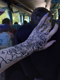 a woman's hand with black and white designs on it, in front of a group of people