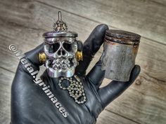 a hand holding a cup with a skull on it and a chain hanging from the top