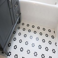 a white bath tub sitting next to a sink in a bathroom with black and white tiles on the floor