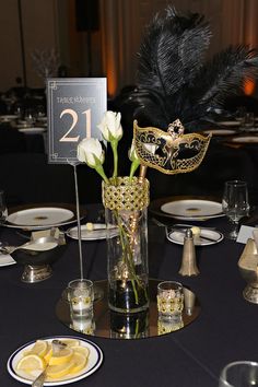 a table topped with a vase filled with white flowers and a mask on top of it