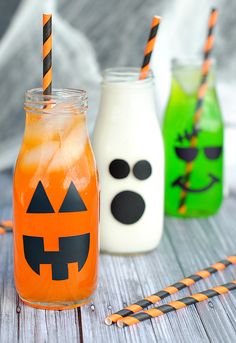 three halloween drinks in mason jars with orange and green striped straws on the table