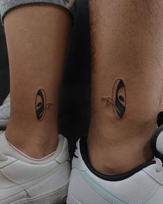 two people with matching tattoos on their legs, one has an eyeball and the other has a tennis racket