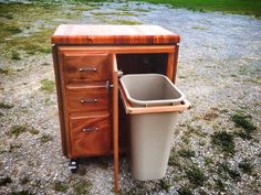 a trash can sitting next to a wooden cabinet on top of a grass covered field