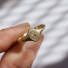 a person is holding a gold ring with a small flower on it's side