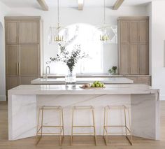 a kitchen with marble counter tops and bar stools next to an island in the middle