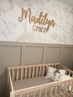 a baby crib in front of a wall with the name madison grace written on it