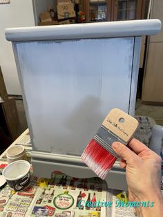 a person holding a paint brush over a cabinet door