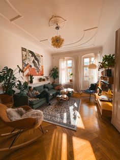 a living room filled with lots of furniture and plants on top of a hard wood floor