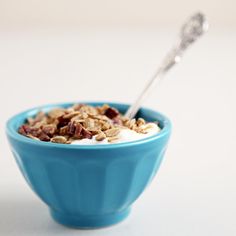 a blue bowl filled with granola and yogurt on top of a white table