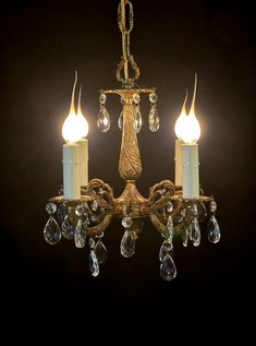 an antique chandelier with three candles and crystal drops on the lightshade