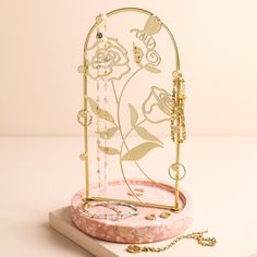 a gold jewelry holder with flowers on it